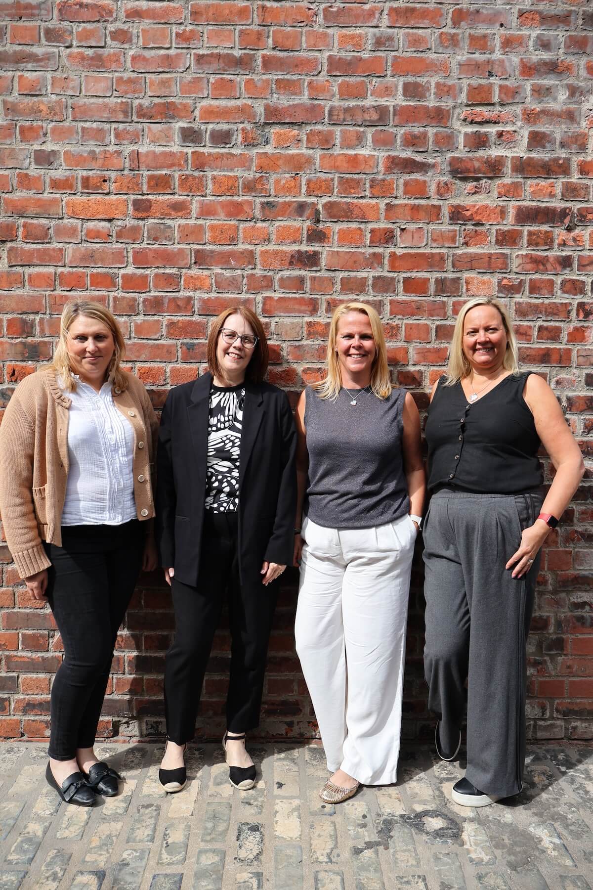4 women standing in front of a brick wall - Oculus HR consultants
